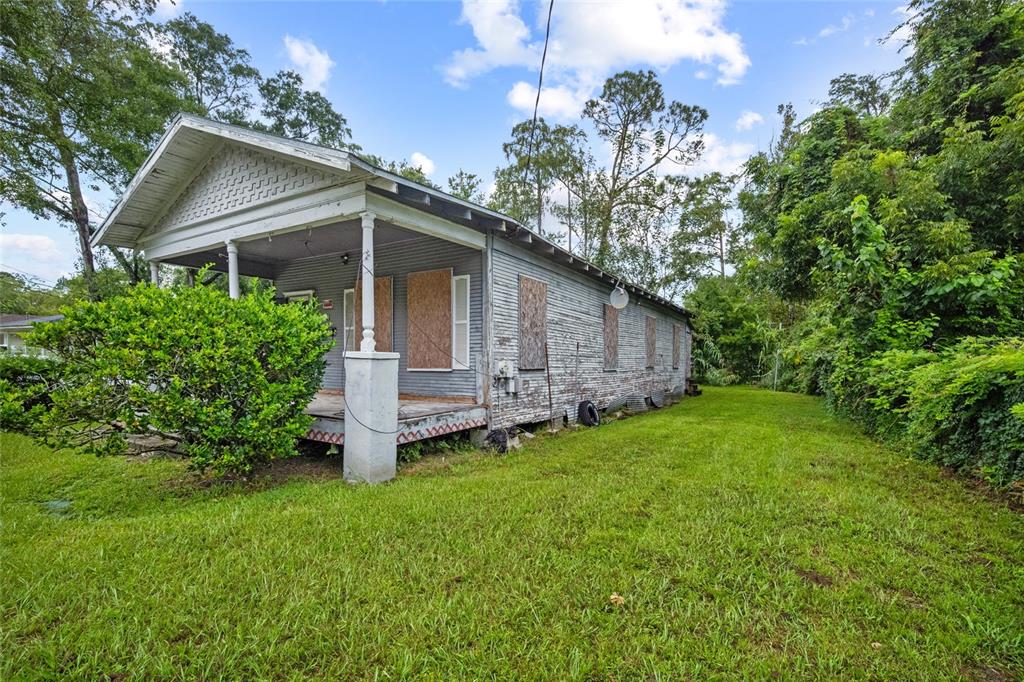 A weathered, single-story house with boarded-up windows and a front porch sits on a lawn — 2117 TUSKEGEE ROAD, JACKSONVILLE, FL