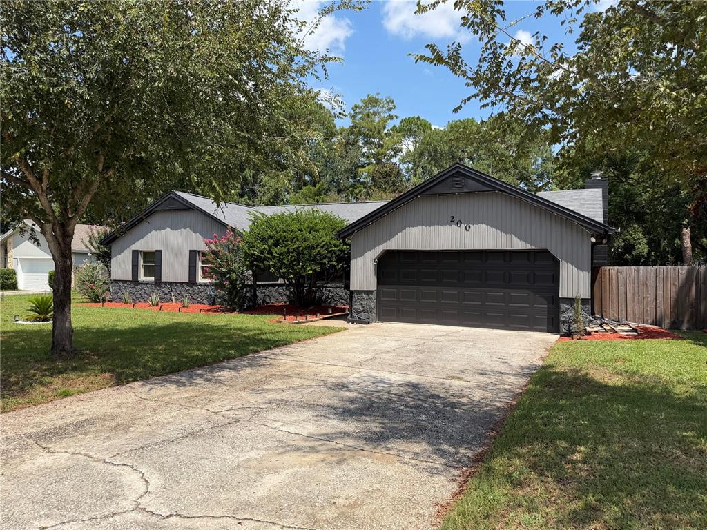 A single-story house with gray vertical siding, a stone base, and a two-car garage — 200 W PANAMA ROAD, WINTER SPRINGS, FL