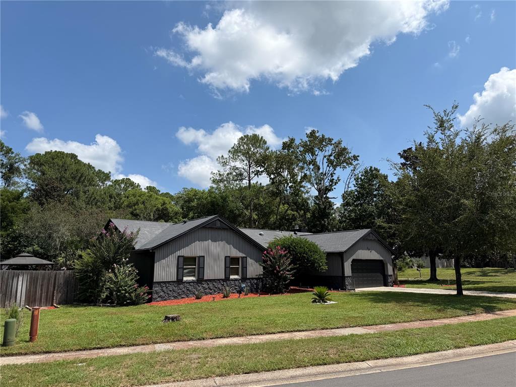 A single-story house with gray vertical siding, a stone base, and an attached garage — 200 W PANAMA ROAD, WINTER SPRINGS, FL