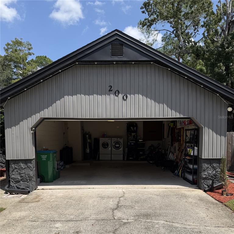 A detached garage with gray vertical siding, stone accents, and an open bay — 200 W PANAMA ROAD, WINTER SPRINGS, FL