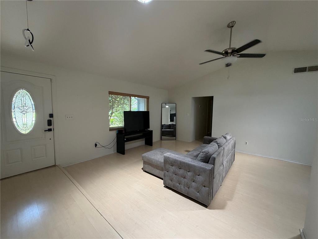 A living room features light wood flooring, a grey sofa, a television, and a ceiling fan — 200 W PANAMA ROAD, WINTER SPRINGS, FL