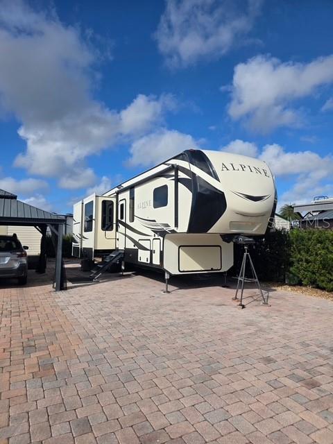 An Alpine fifth-wheel recreational vehicle is parked on a paved driveway under a blue sky — 2537 LEMONWOOD AVENUE, CLERMONT, FL