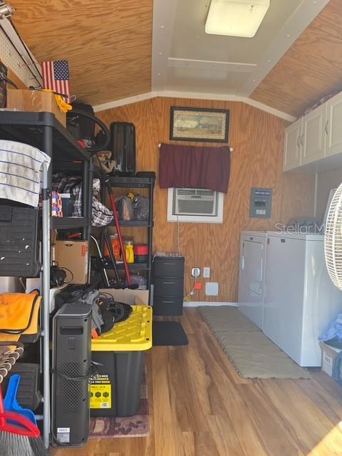 A utility room features wood-paneled walls, a washer and dryer, and black storage shelving — 2537 LEMONWOOD AVENUE, CLERMONT, FL