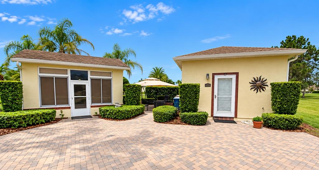 A light-colored house exterior features a paved walkway, manicured hedges, and a glass storm door — 326 NOLANE LANE, POLK CITY, FL