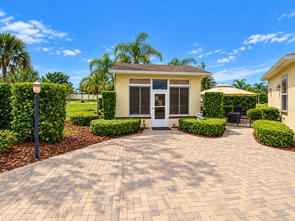 A small, tan-colored house with a large glass sliding door is surrounded by manicured landscaping — 326 NOLANE LANE, POLK CITY, FL
