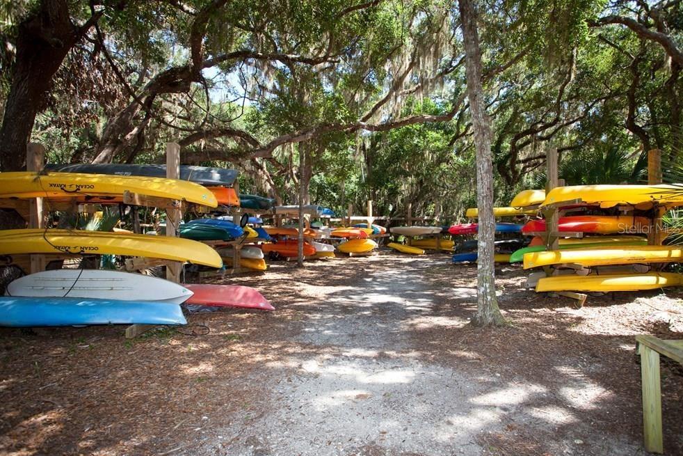A wooden rack stores numerous colorful kayaks under a canopy of large oak trees — 3 SAN LUIS LANE, PALM COAST, FL