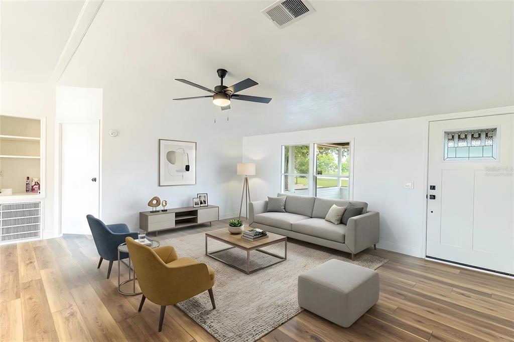 A bright living room features a gray sofa, yellow armchair, wood flooring, and ceiling fan — 8025 ALTURAS BABSON PARK CUTOFF ROAD, BARTOW, FL