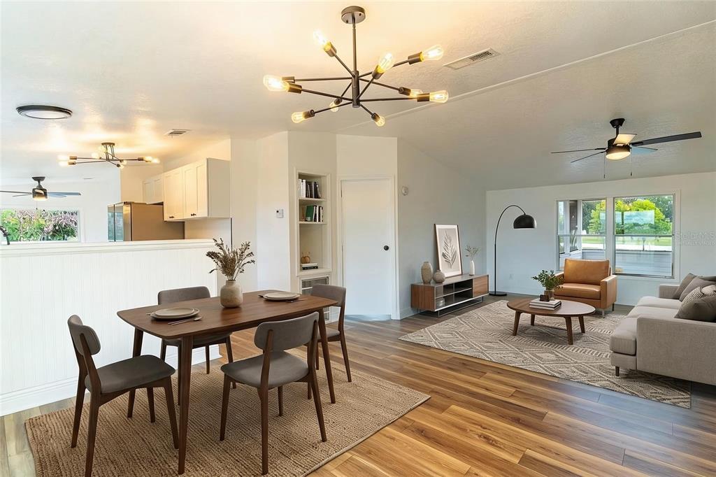 An open-concept living and dining area features wood-look flooring, a modern chandelier, and neutral walls — 8025 ALTURAS BABSON PARK CUTOFF ROAD, BARTOW, FL