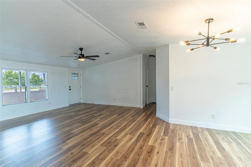 A bright living area features wood-look flooring, a ceiling fan, and a modern chandelier — 8025 ALTURAS BABSON PARK CUTOFF ROAD, BARTOW, FL