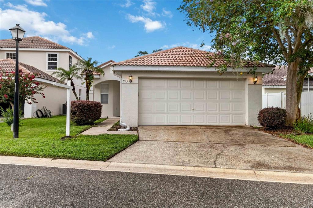 A single-story house with a white garage door, a tiled roof, and a small front lawn — 923 TORREY PINE DRIVE, WINTER SPRINGS, FL