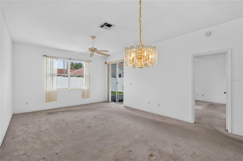 An empty living room with beige carpet, a ceiling fan, and a gold-toned chandelier — 923 TORREY PINE DRIVE, WINTER SPRINGS, FL
