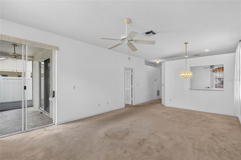 A living room with beige carpet, a ceiling fan, and a sliding glass door — 923 TORREY PINE DRIVE, WINTER SPRINGS, FL