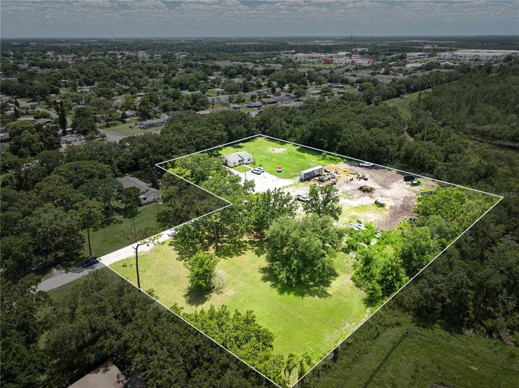 An aerial view shows a house on a large, partially cleared, grassy lot with trees — 500 FORE LANE, KISSIMMEE, FL