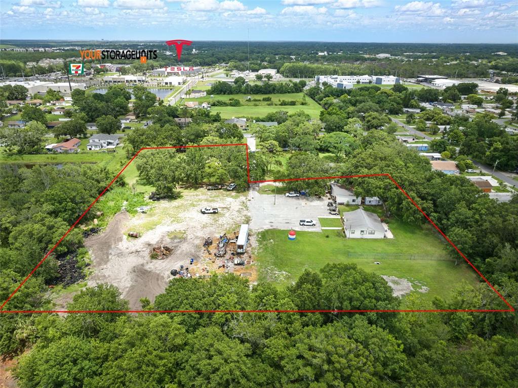 An aerial view shows a large, partially cleared lot with two buildings and scattered debris — 500 FORE LANE, KISSIMMEE, FL