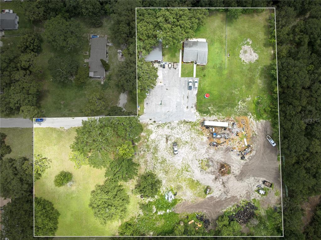 This aerial view shows a large property with two houses, a paved driveway, and cleared land — 500 FORE LANE, KISSIMMEE, FL