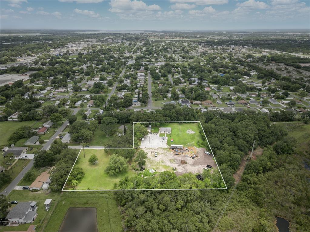 An aerial view shows a large, partially cleared lot with a small building and trees — 500 FORE LANE, KISSIMMEE, FL
