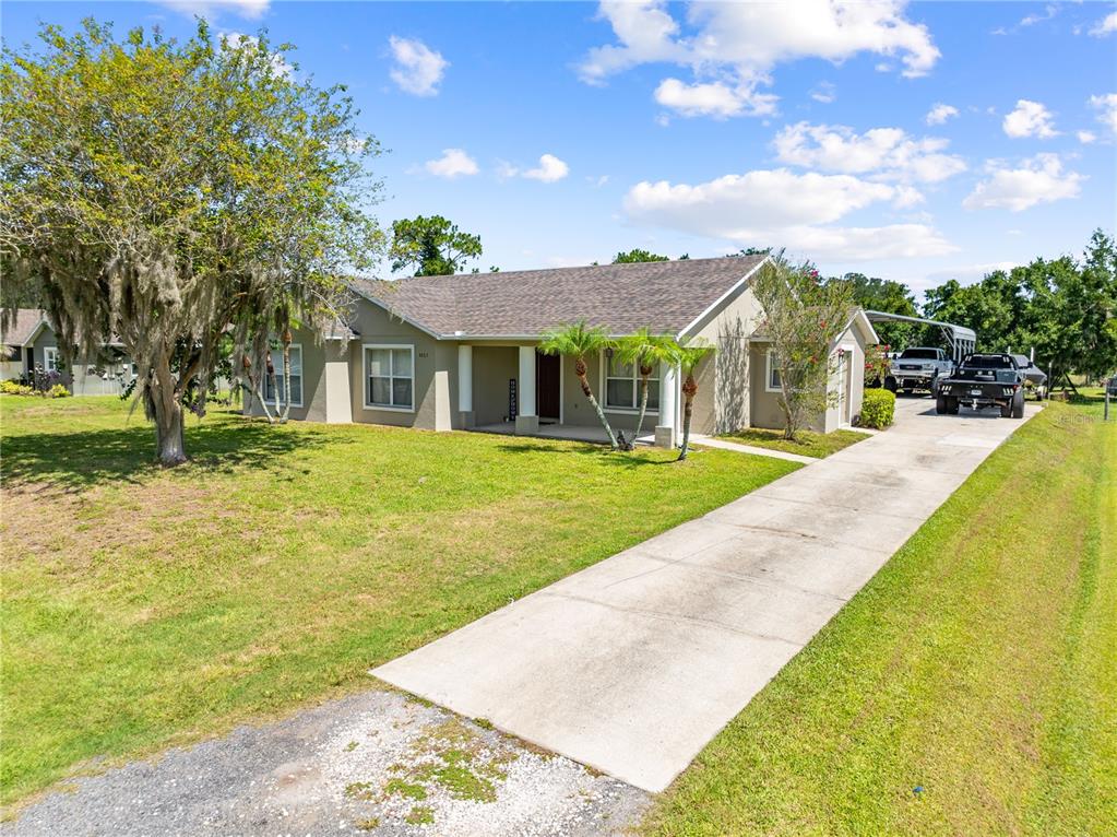 A single-story house with a concrete driveway, a front porch, and a large oak tree — 4865 MEADOW DRIVE, ST CLOUD, FL