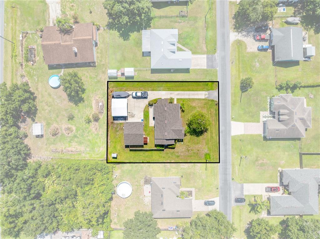 An aerial view shows a residential property with a house, detached garage, and driveway — 4865 MEADOW DRIVE, ST CLOUD, FL