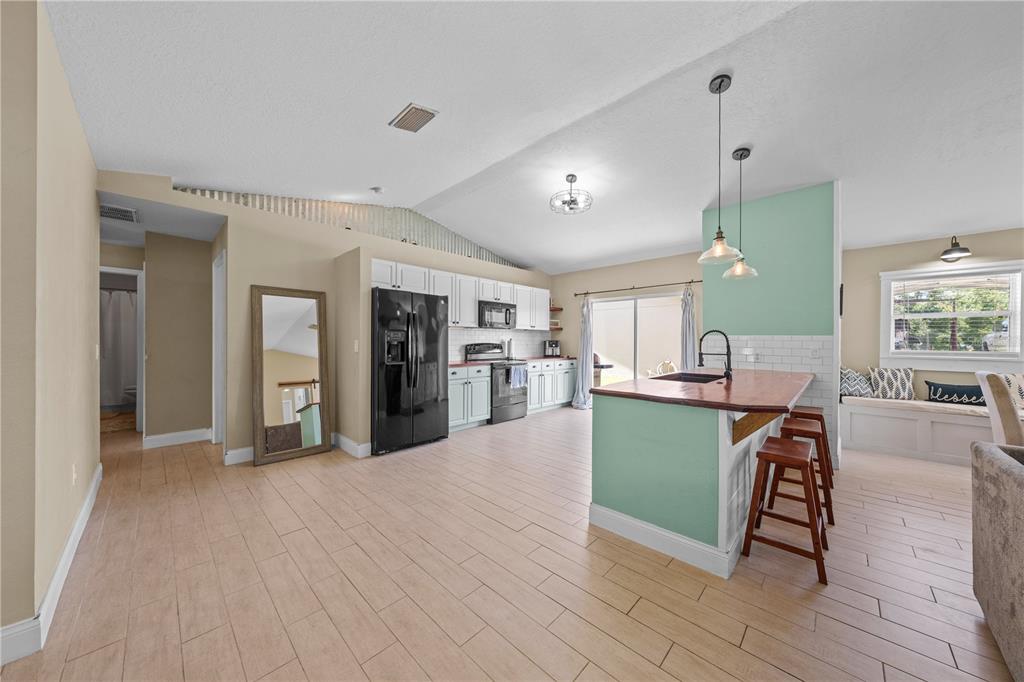 A kitchen with light wood-look flooring, mint green accents, and a wooden island countertop — 4865 MEADOW DRIVE, ST CLOUD, FL