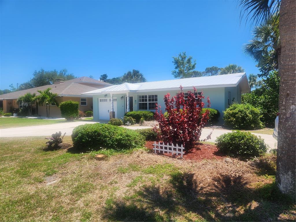 A light blue single-story house with a white metal roof and a landscaped front yard — 316 ALBA STREET E, VENICE, FL