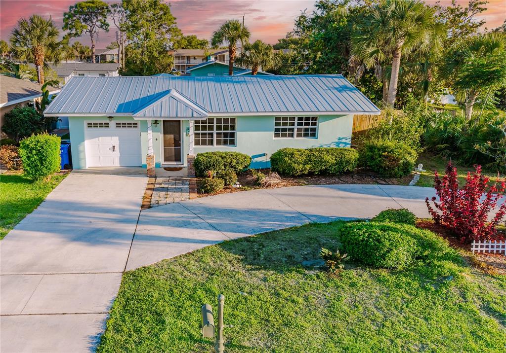 A single-story house with a light blue exterior, metal roof, and a concrete driveway — 316 ALBA STREET E, VENICE, FL