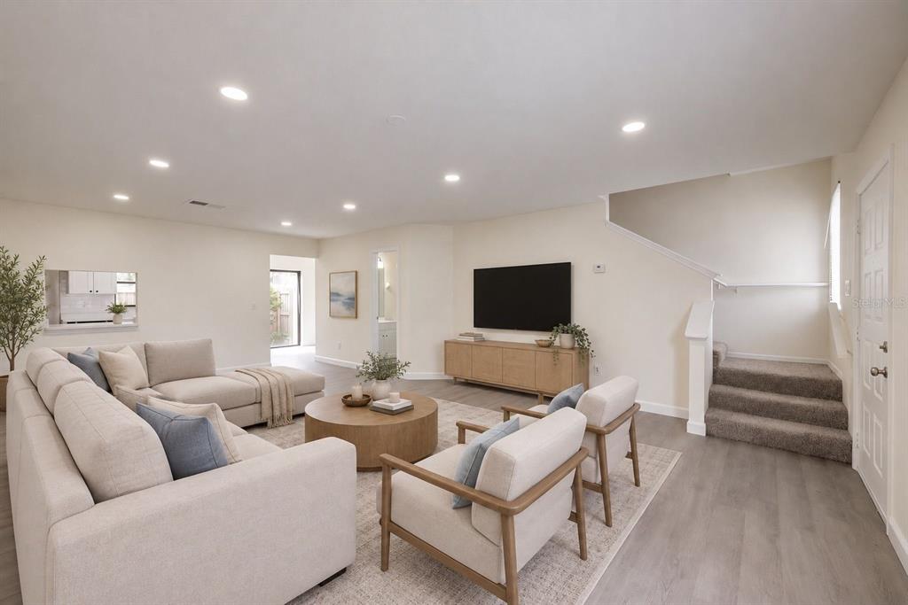 A living room features a sectional sofa, two armchairs, a television, and stairs with carpet — 6266 YORKTOWN DRIVE UNIT 179, ORLANDO, FL