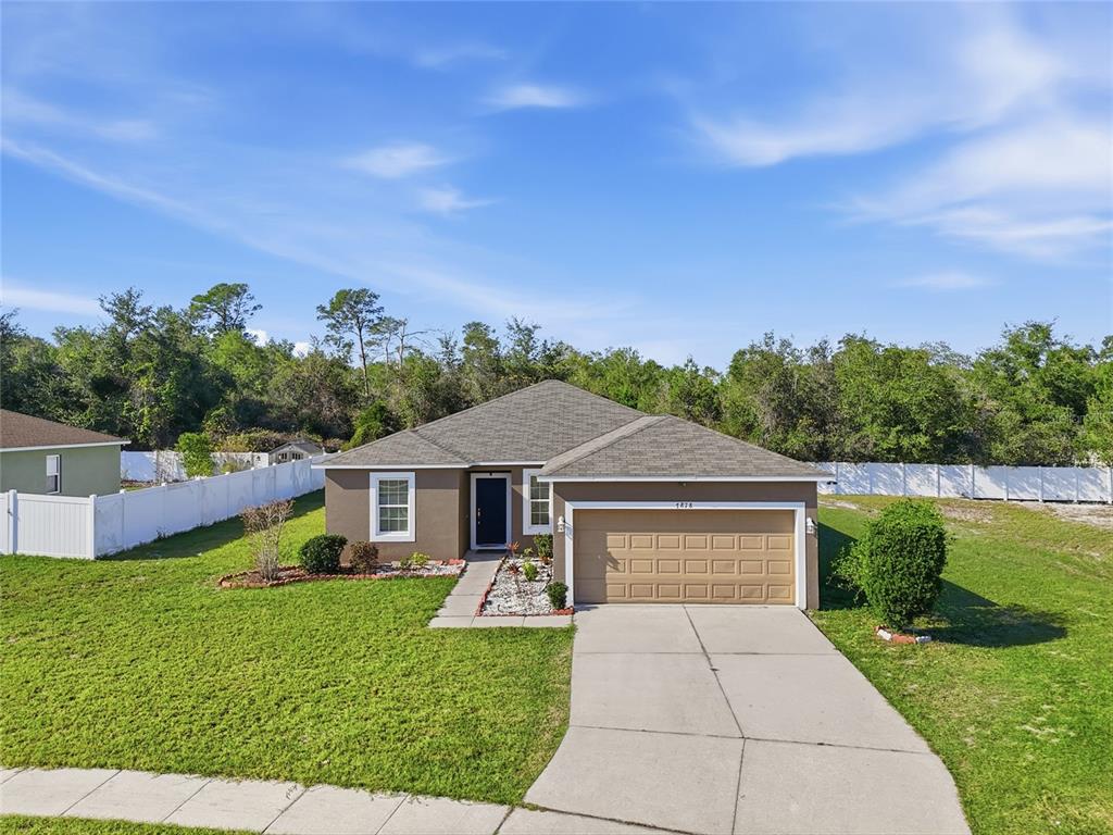 A single-story house with a brown exterior, a two-car garage, and a white vinyl fence — 7878 TANBIER DRIVE, ORLANDO, FL