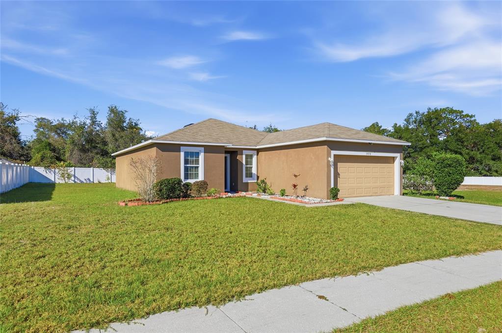 A single-story tan stucco house with a two-car garage and a front lawn — 7878 TANBIER DRIVE, ORLANDO, FL