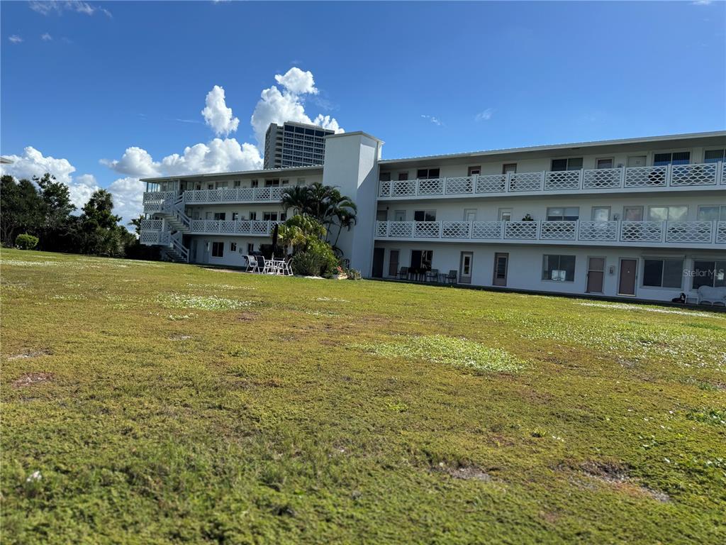 A three-story apartment building with exterior walkways and balconies overlooks a large grassy lawn — 767 JOHN RINGLING BOULEVARD UNIT 2, SARASOTA, FL