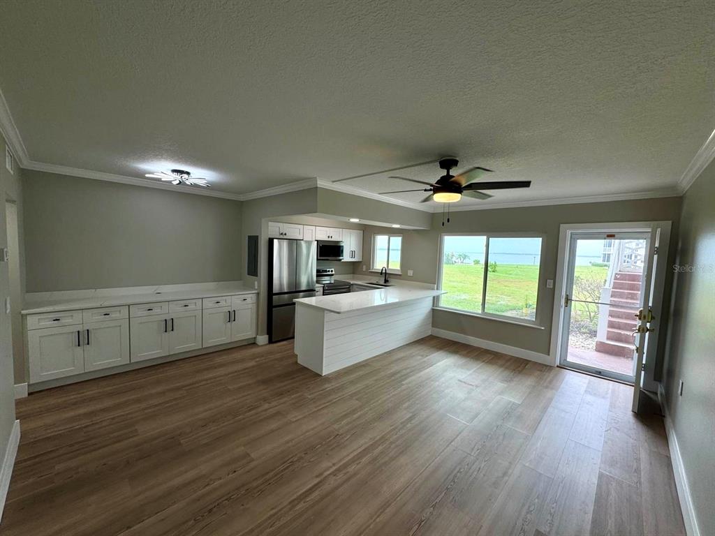 A kitchen with white cabinets, a breakfast bar, and wood-look flooring opens to a patio — 767 JOHN RINGLING BOULEVARD UNIT 2, SARASOTA, FL