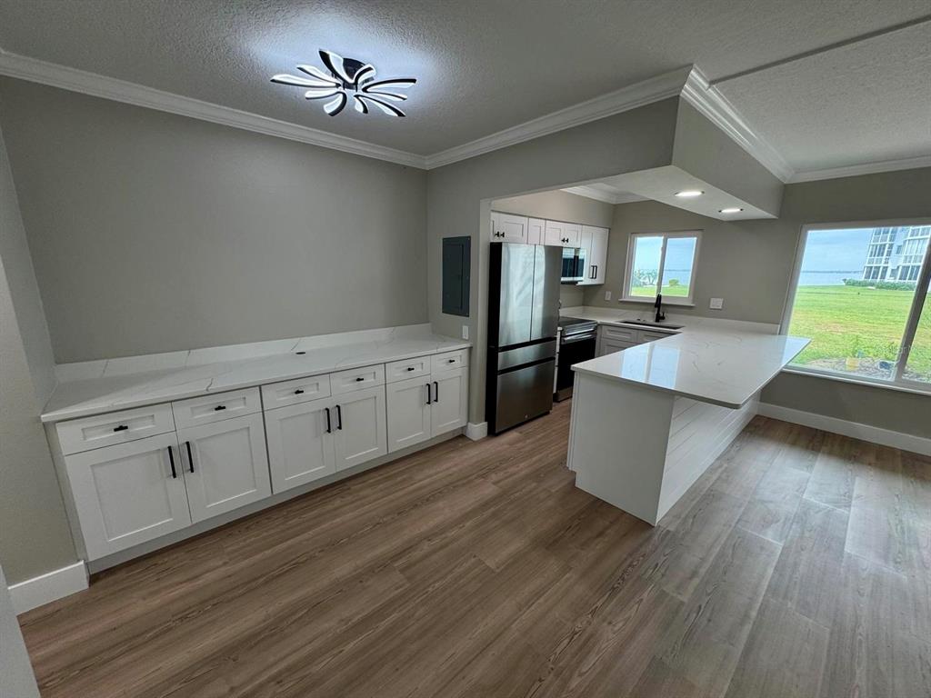 A kitchen features white cabinets, quartz countertops, stainless steel appliances, and wood-look flooring — 767 JOHN RINGLING BOULEVARD UNIT 2, SARASOTA, FL