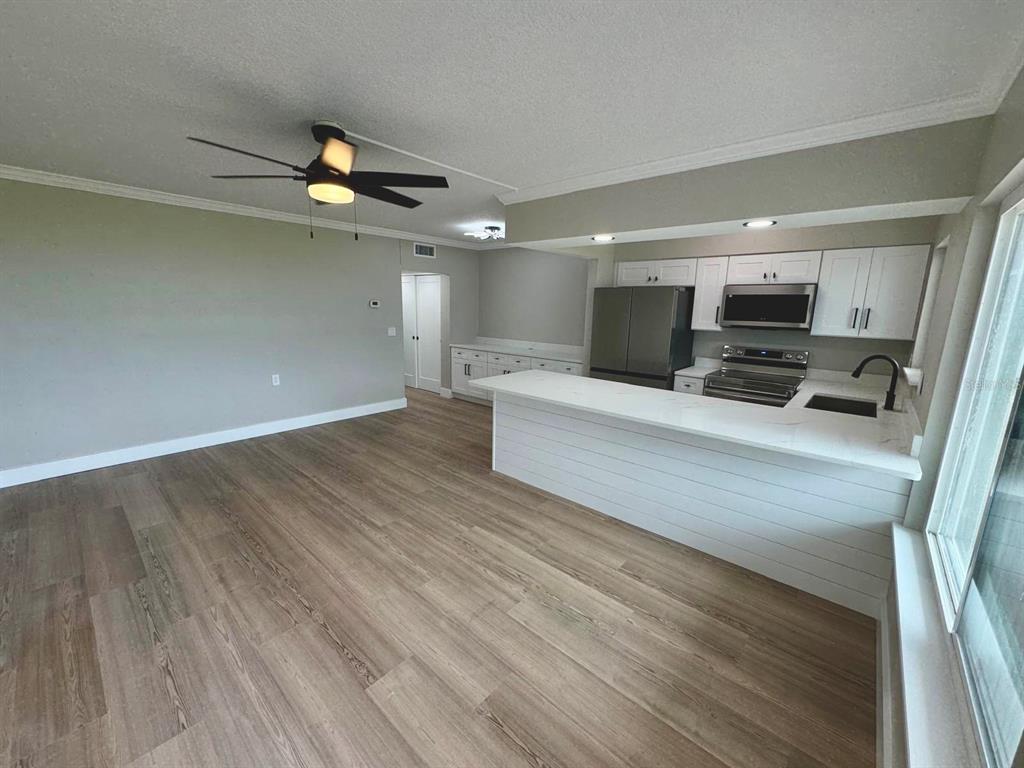 A kitchen with white cabinets and a breakfast bar opens into a living area — 767 JOHN RINGLING BOULEVARD UNIT 2, SARASOTA, FL