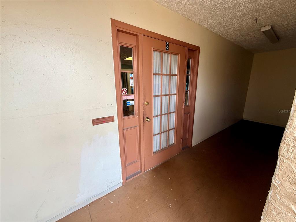 A tan exterior door with a glass pane and the number three sits under an overhang — 7236 STATE ROAD 52 UNIT 3, HUDSON, FL