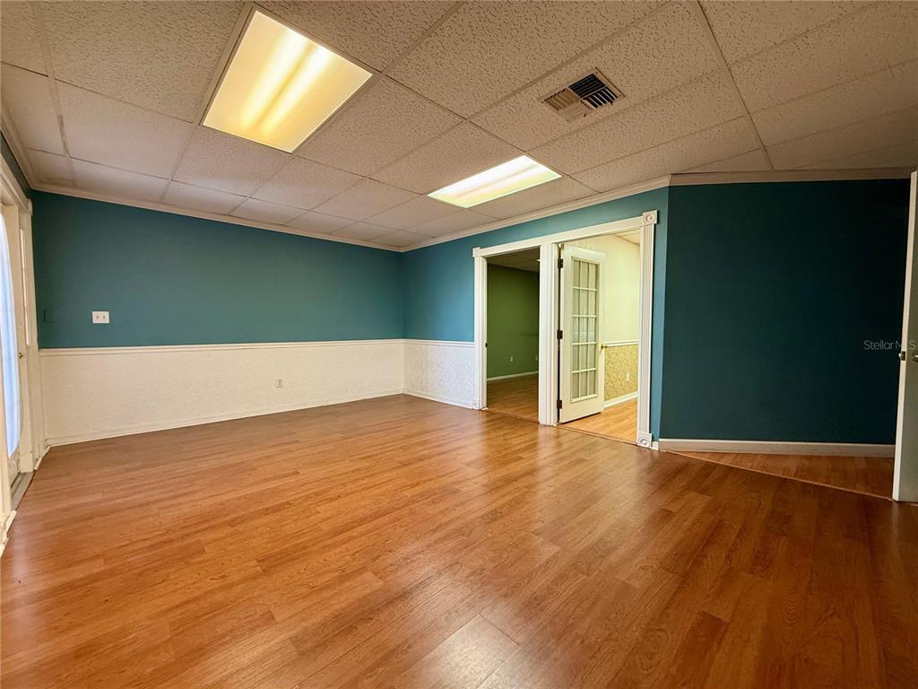 An office room features teal walls, white wainscoting, wood-look flooring, and a drop ceiling — 7236 STATE ROAD 52 UNIT 3, HUDSON, FL