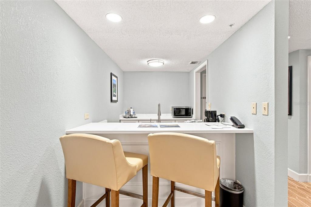 A wet bar area features a white countertop, two upholstered bar stools, and recessed lighting — 36750 US HIGHWAY 19 N UNIT 16204, PALM HARBOR, FL