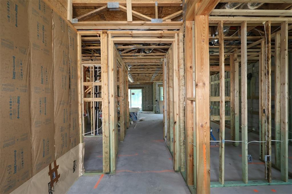 An interior view of a house under construction showing wooden wall framing and insulation batts — 2873 SWEETGRASS LANE, ZELLWOOD, FL