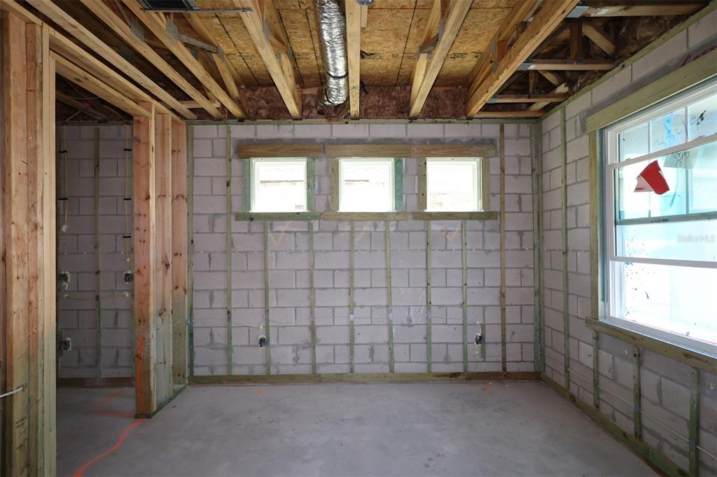 An unfinished room with concrete block walls, exposed ceiling joists, and three small rectangular windows — 2873 SWEETGRASS LANE, ZELLWOOD, FL