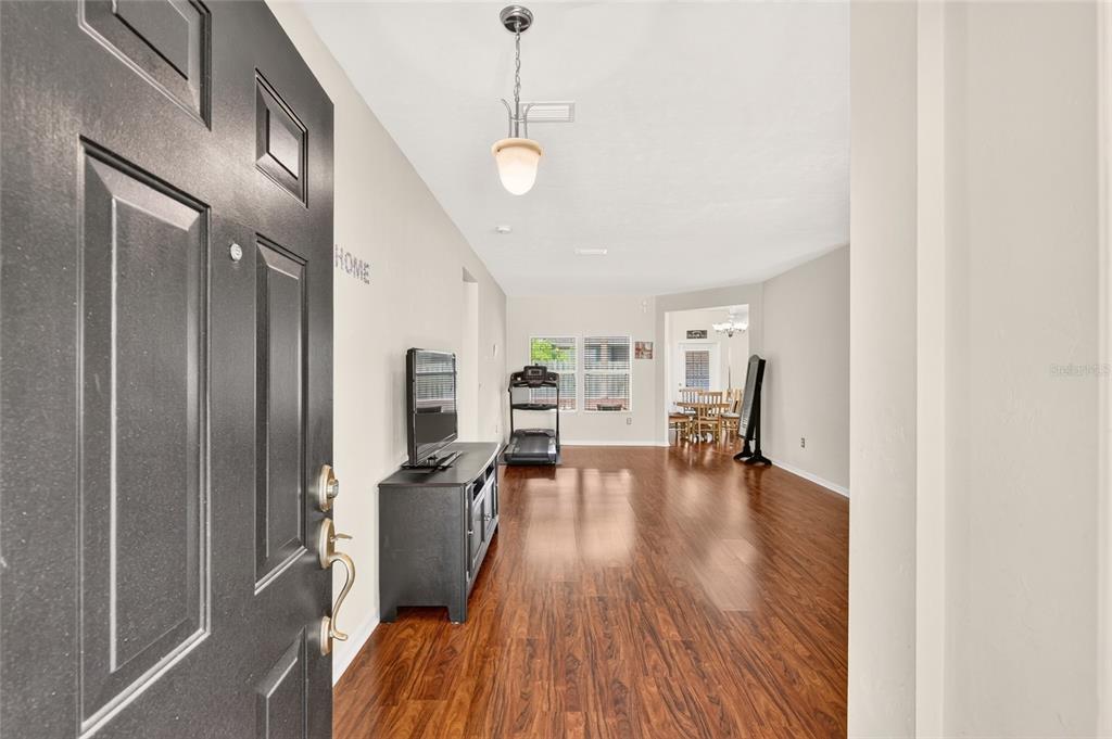 An entryway opens into a living area with wood-look flooring and a treadmill — 8391 SW 75TH ROAD, GAINESVILLE, FL