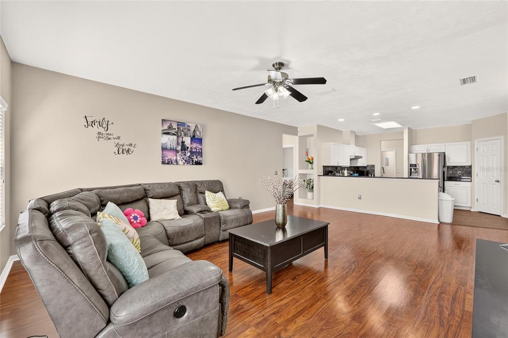 A living room with a grey sectional sofa, dark wood coffee table, and open kitchen — 8391 SW 75TH ROAD, GAINESVILLE, FL