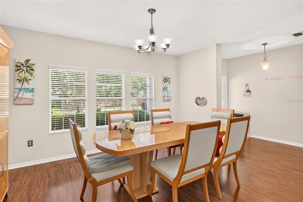 A dining room features a wooden table, six chairs, a chandelier, and wood-look flooring — 8391 SW 75TH ROAD, GAINESVILLE, FL