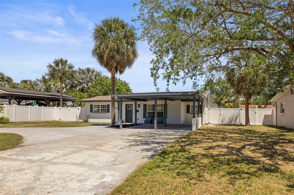 A single-story house with a carport, white vinyl fencing, and palm trees in the yard — 4327 HUNTINGTON STREET NE, ST PETERSBURG, FL