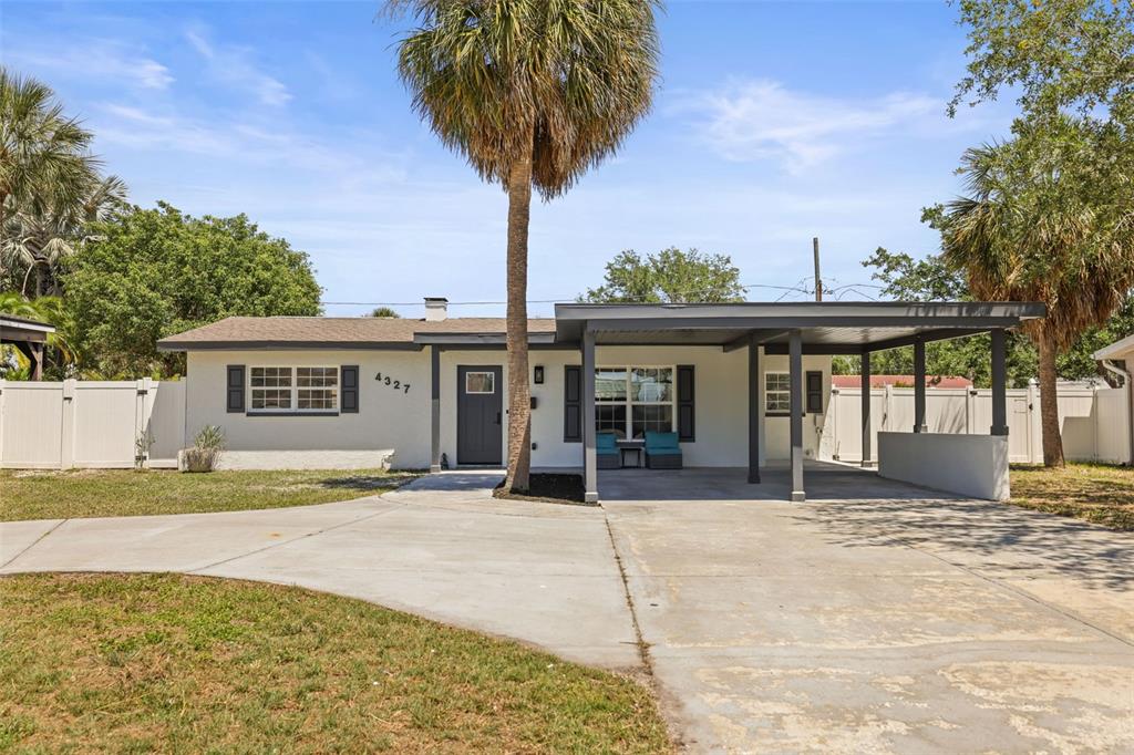 A single-story house with a white exterior, a dark front door, and an attached carport — 4327 HUNTINGTON STREET NE, ST PETERSBURG, FL