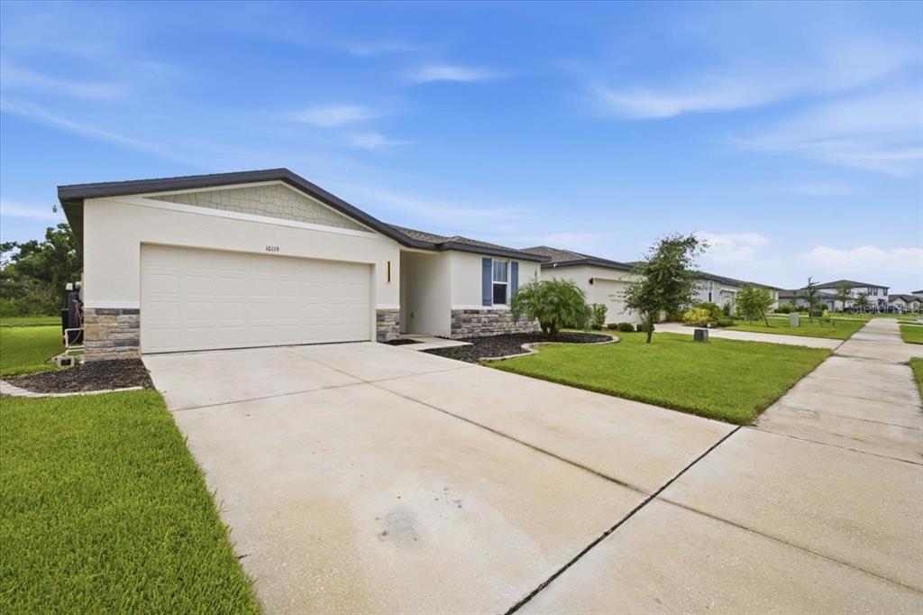 A single-story house with a beige stucco exterior, stone accents, and a two-car garage — 10119 DAYBREAK GLEN, PARRISH, FL