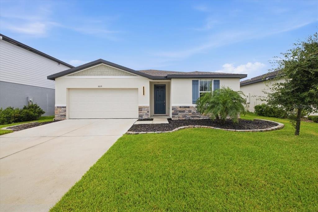 A single-story house with a white stucco facade, stone accents, and a two-car garage — 10119 DAYBREAK GLEN, PARRISH, FL