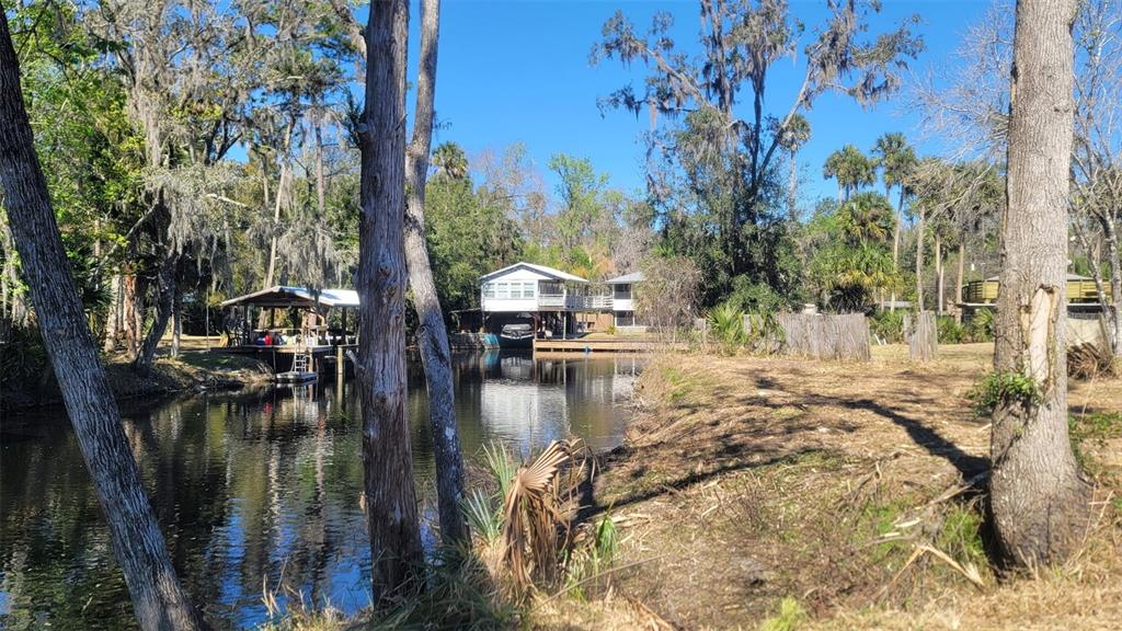 A canal flows past a stilt house and a boat dock surrounded by trees — 55813 SAM STREET, ASTOR, FL