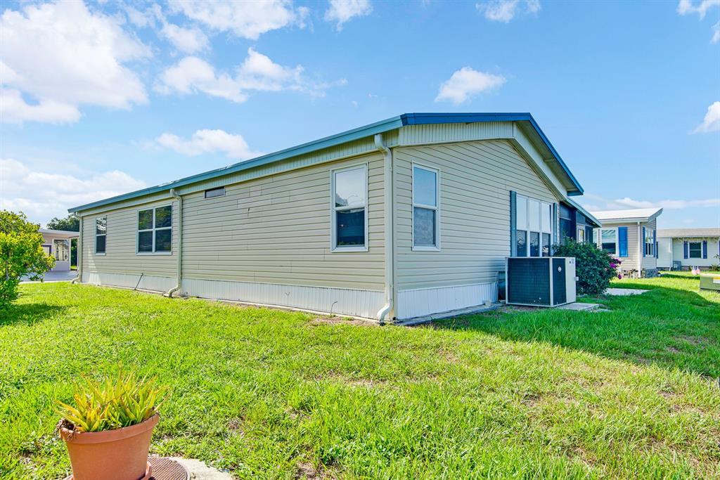 A light-colored manufactured home sits on a grassy lot under a blue sky — 9107 34TH AVENUE E, PALMETTO, FL