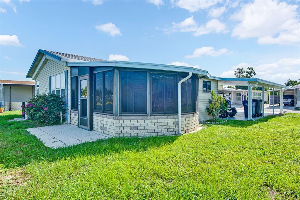 A mobile home exterior features a screened-in porch, a brick base, and a covered carport — 9107 34TH AVENUE E, PALMETTO, FL