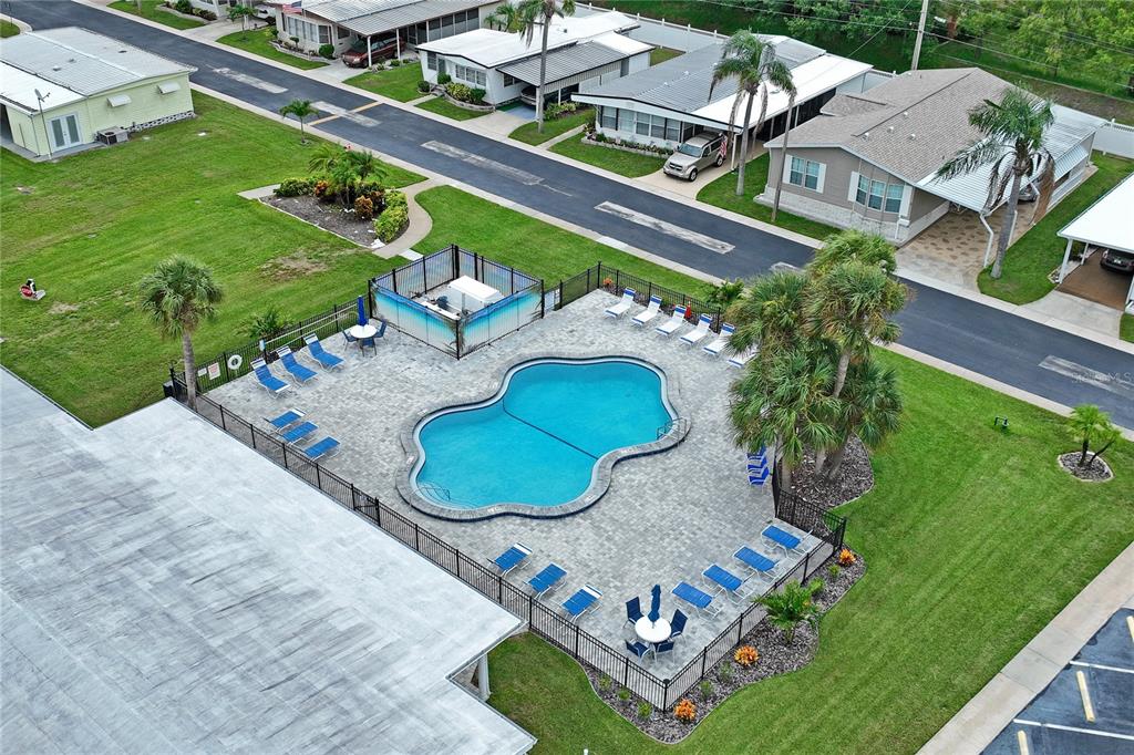 An aerial view shows a community swimming pool surrounded by lounge chairs and palm trees — 2000 E BAY DRIVE UNIT 25, LARGO, FL