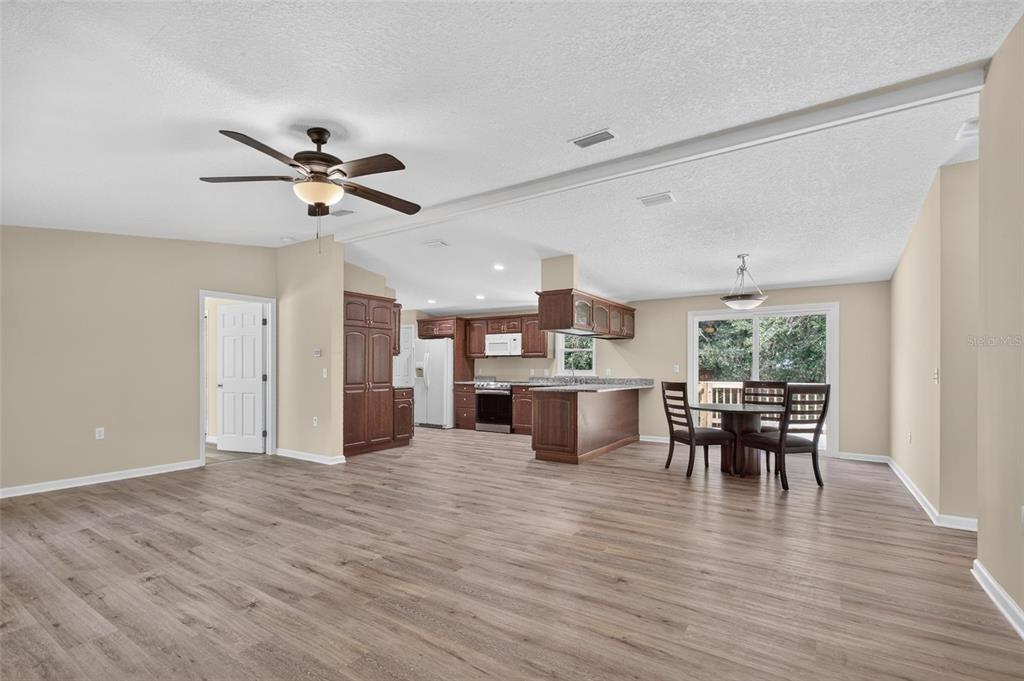 An open-concept kitchen and dining area features wood-look flooring, dark wood cabinetry, and a ceiling fan — 6593 CROOKED CREEK LANE, ST AUGUSTINE, FL