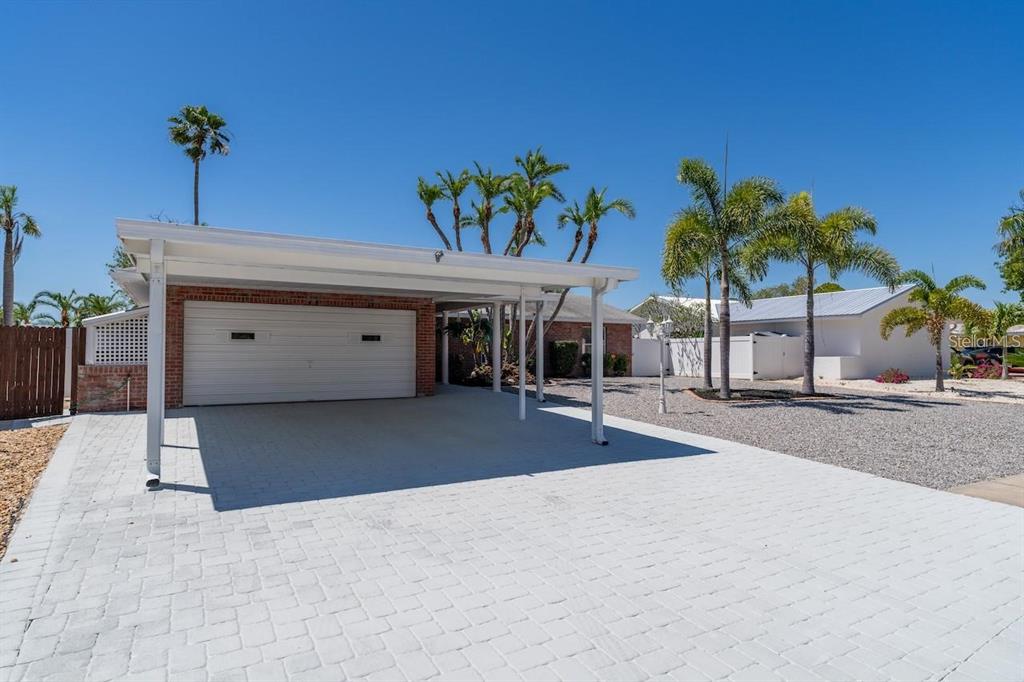 A white carport with a garage door sits in front of a brick house exterior — 6512 KING PALM WAY, APOLLO BEACH, FL